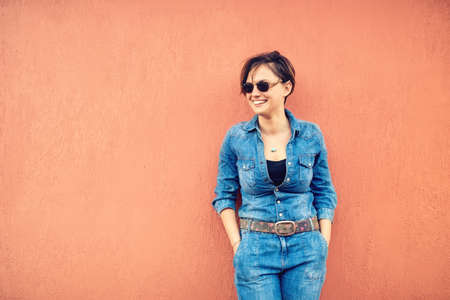 fashion lifestyle with beautiful funny woman on terrace wearing modern jeans outfit, sunglasses and smiling.の写真素材