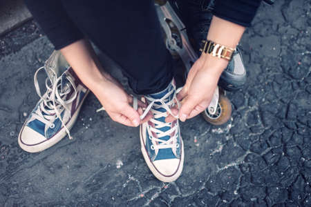 Hipster wearing sneakers, teenager tieing laces at sport shoes. Urban lifestyle with footwear and...