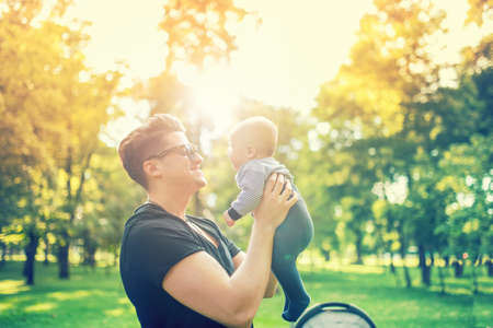 Young father holding delicate newborn infant in arms outdoor in park. Happy parenting concept, father's day and familyの写真素材