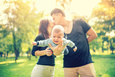 Young married couple holding newborn child and kissing. Happy Family, father's and mother's day concept.の写真素材