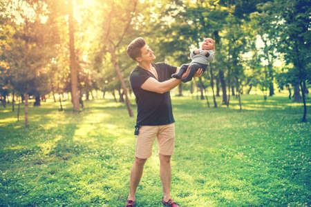 Portrait of father and son having fun in park, father holding baby, infant. Concept of family day in the park with young parentsの写真素材