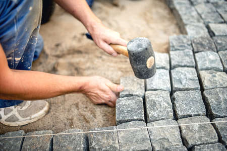 Worker creating pavement using cobblestone blocks and granite stonesの写真素材