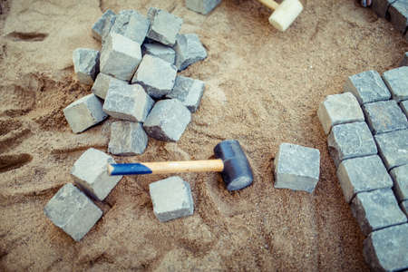 Stone pavement blocks, on sand, with tools and construction details. Laying the pavement cobblestone for outdoor terraceの写真素材