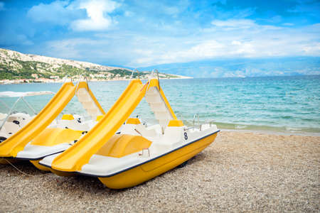 Beach paddle yellow boats, vacation fun details. Rental paddle boats on shore, on beach in exotic resortの写真素材