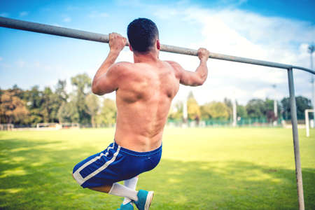 Athletic fitness trainer, basketball and football player training out on the field. Chinups and Pullups trainingの写真素材