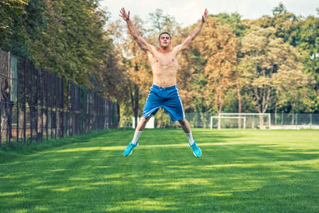 Shirtless handsome man working out in park, cross fit training. Athletic man jumping and doing exercises outdoor, on a summer day.の写真素材