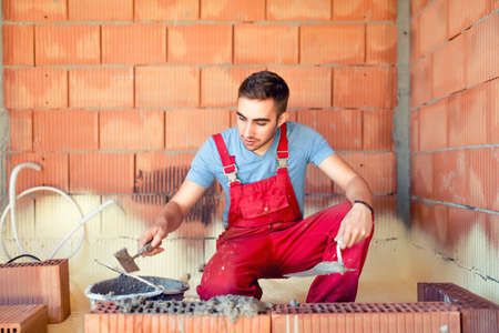 portrait of mason working and building brick walls. Industrial, professional constructor renovatingの写真素材
