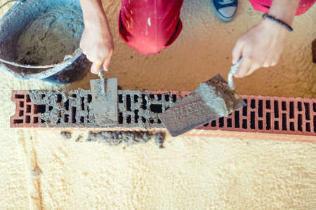 close-up of Construction worker building walls and fixing bricks with mortar and putty knifeの写真素材