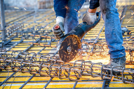 construction industry details - worker cutting steel bars using angle grinder mitre saw.の写真素材