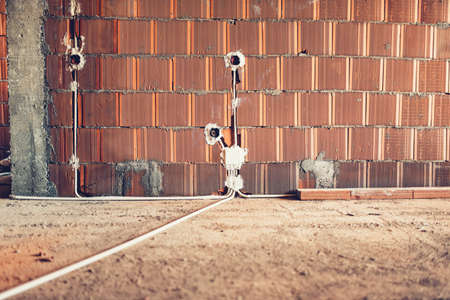 electric sockets installation in brick walls at house construction siteの写真素材