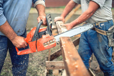workers, handymen cutting timber wood using mechanical chainsaw.の写真素材