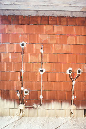 house construction site with energy efficient materials, thermal insulation and brick walls with plugs and electricity pipesの写真素材