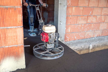 cement smoothing trowel machinery with worker. flooring smoothing at new house construction site