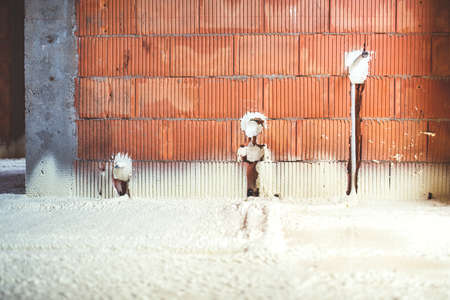 thermal insulation with spray foam, brick walls and electricity lines at construction siteの写真素材
