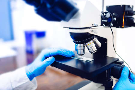 Details of medical laboratory, scientist hands using microscope for chemistry. Engineer Testing...