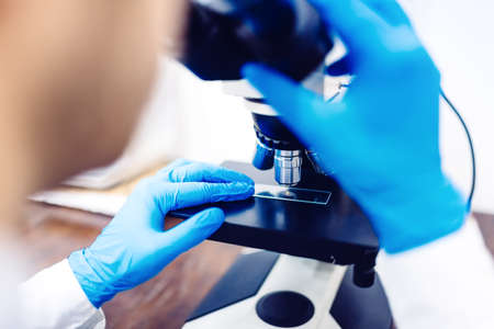 Scientist using microscope to examine small chemical probes. Medical equipment and laboratory samplesの写真素材