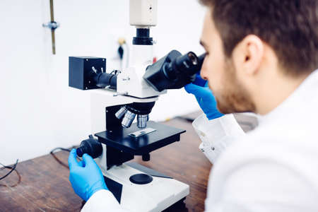Scientist looking through a microscope in a laboratory, testing samples and probesの写真素材