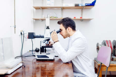 scientist with microscope, examining samples and contaminated probes in special laboratoryの写真素材