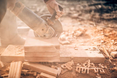 Industrial worker on construction site, working in debris and dus, sawing and chopping bricks with angle grinderの写真素材