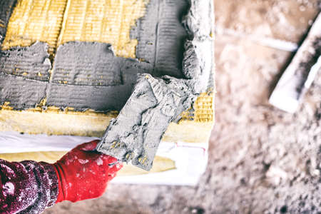 close-up of worker hand on industrial construction site using a trowel and applying adhesive on thermal insulation panelsの写真素材