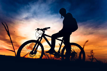 silhouette of biker riding mountain bike at sunsetの写真素材