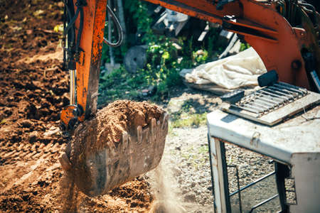 industrial excavator moving earth on construction site. Close-up of bucket full of earth