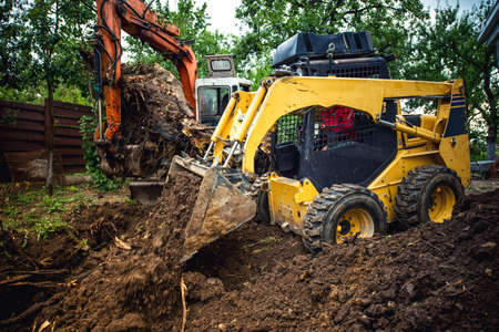 Landscaping works with bulldozer and excavator at home construction site
