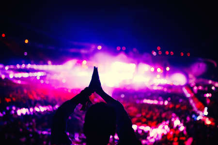 Silhouette of woman clapping and enjoying a concert at music festival.の写真素材