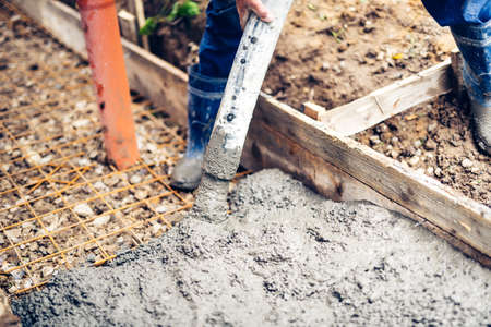 Detail of construction site - worker pouring cement and concrete with pump tube on reinforcement...