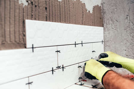 Renovation in progress. Industrial worker installing bathroom ceramic tiles