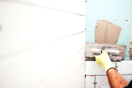 renovation in progress, construction details, close up of worker hands using trowel and adding...