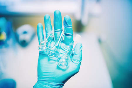 Close up of scientist rubber glove holding small glass containers. Chemical Engineer working with analyzing tubesの写真素材