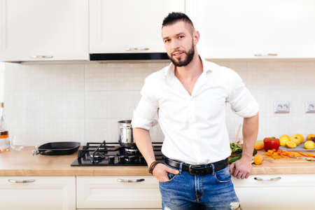 modern lifestyle, man dressed with shirt and jeans cooking and preparing food in kitchenの写真素材