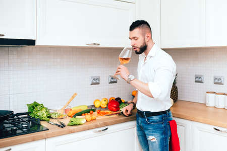 male chef tasting rose wine, perfect match for salad in modern kitchenの写真素材