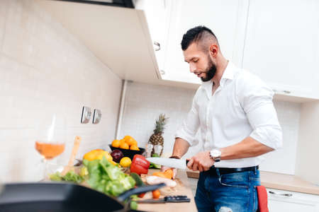Valentine's day concept: Classy man with elegant shirt cooking dinner for girlfriend. cook cutting vegetables and preparing salad. の写真素材