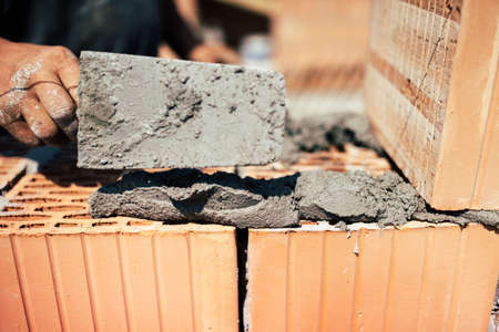 Details of industrial bricklayer installing bricks on construction siteの写真素材