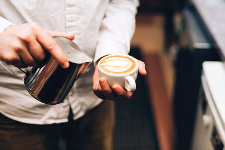 Barista pouring perfect cappuccino into cup, making a delicious morning drinkの写真素材