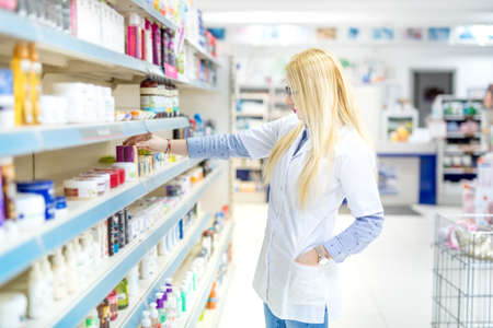 Sexy blonde pharmacist selling antibiotics and prescription drugs. Pharmaceutical medical details
の写真素材