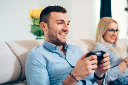 Attractive man playing videogames  with wife or girlfriend on general console. 