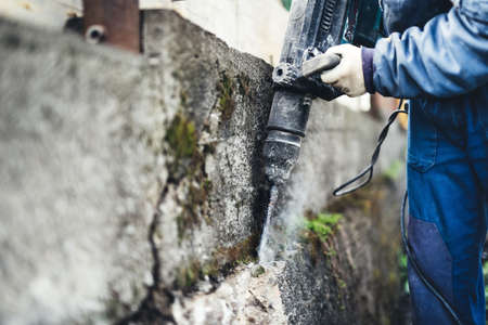 Worker using industrial construction tool, industrial jackhammer with demolition debris and cementの写真素材