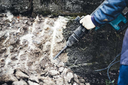 Industrial construction work demolishing a concrete wall with jackhammer. Details of constructionの写真素材