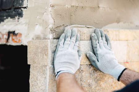 details of construction worker hands using mortar and stone for paving wallsの写真素材