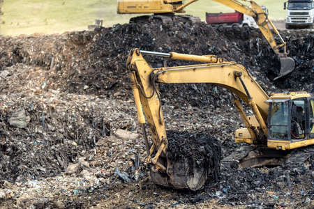 Monster industrial excavator digging into trash at urban dumping groundsの写真素材