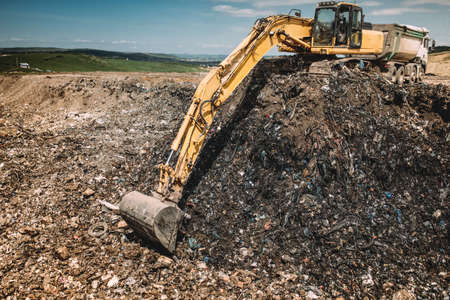 Industrial machinery excavating garbage. Close up of heavy duty excavator using scoop and workingの写真素材