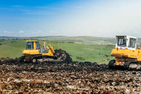 Industrial bulldozers working on construction site. Details of wasteland, garbage disposal dumping...