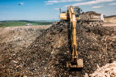 Urban city waste dumping grounds with excavator loading trucksの写真素材