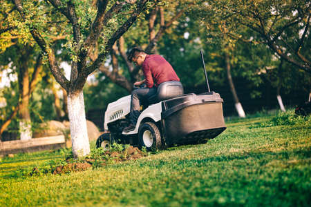 Male worker carefully trimming lawn. Grass cutter occupation in industrial field