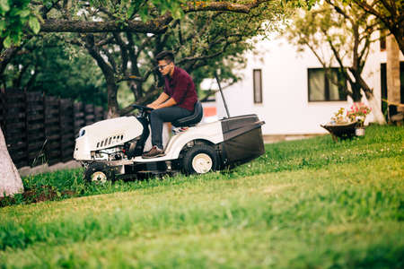 Man working in garden, relaxing day in weekend and cutting grass with lawn mowerの写真素材