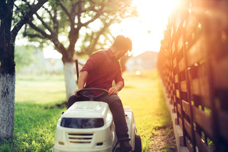 Gardening details during sunset hour. Man working on ride-on lawn mowerの写真素材