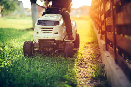Close up details of landscaping and gardening. Worker riding industrial lawnmowerの写真素材